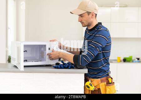 Young repairman fixing and repairing microwave oven. Stock Photo