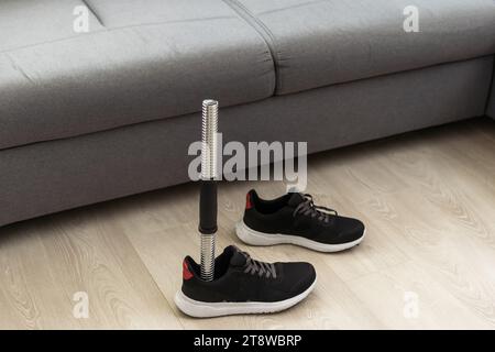 prosthetic leg disability on above knee transfemoral leg prosthesis artificial device stands on feet on floor, close up.  Stock Photo