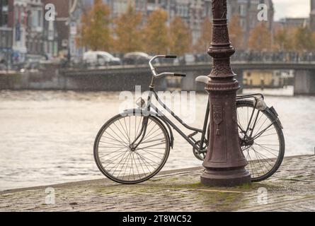 Old dutch bike by the canal in Amsterdam on a rainy autumn day Stock Photo