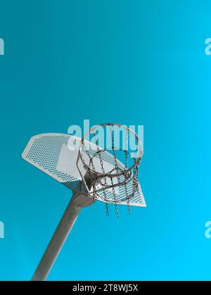 Low angle of basketball hoop with net and metallic pole against cloudless blue sky on sports ground on sunny day Stock Photo