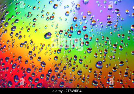 Water drops of different sizes close-up macro on rainbow multicolored smooth surface Stock Photo