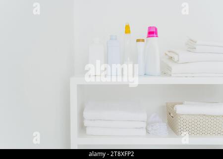 Neatly organized laundry shelf with clean towels and various detergents Stock Photo