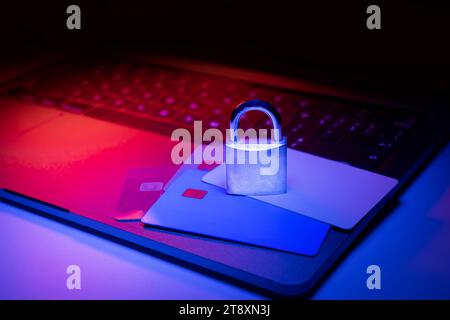 Closeup of a padlock on a laptop and credit card illuminated with blue and red light. Phishing, cybersecurity danger or ransomware attack. Encrypted p Stock Photo