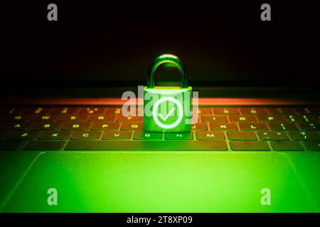 Closeup of a padlock on a laptop illuminated with green light. Phishing, cybersecurity danger or ransomware attack.The padlock is unlocked and display Stock Photo