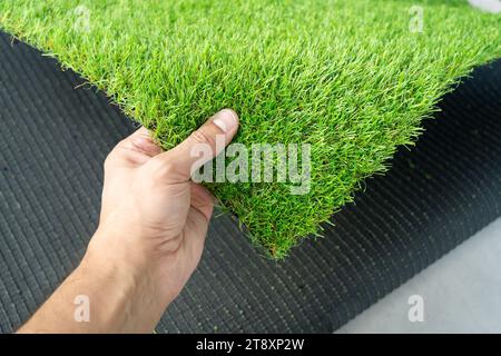Close up of hand holding an artificial grass roll. Greenering with an artificial turf Stock Photo