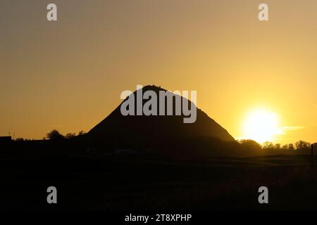 The sun setting behind the hill of North Berwick Law, North Berwick, East Lothian, Scotland, UK Stock Photo