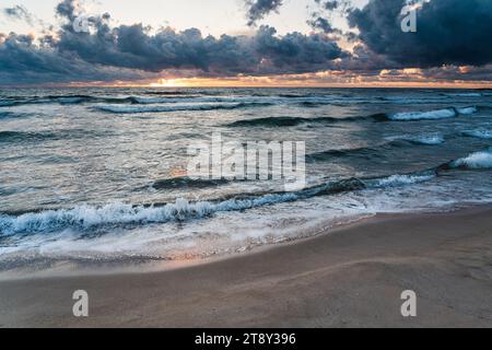 waves of the black sea, sandy beach and sun hidden behind dark clouds Stock Photo