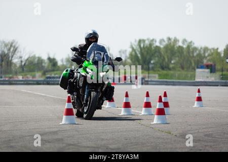 motorcycle rider on a green adventure bike riding through cones Stock Photo