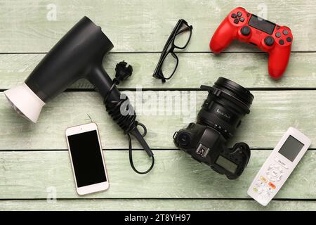 Modern gadgets with eyeglasses on green wooden background Stock Photo