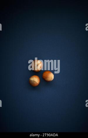 Three whole hazelnuts on a blue background seen from above Stock Photo