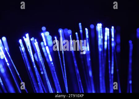 Optical fiber strands transmitting blue light on black background, closeup Stock Photo