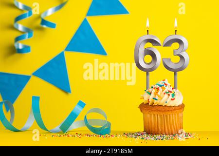 Birthday candle number 63 with cupcake - Yellow background with blue pennants Stock Photo