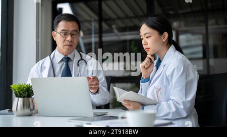 Young beautiful female doctor is asking for advice from a professional and experienced senior male doctor in the office room, brainstorming and consul Stock Photo