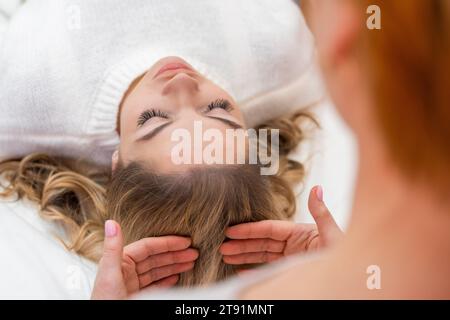 Healer performing by lightly touched set of 32 points of access bars on woman head, stimulating positive change thoughts and emotions. Alternative Stock Photo