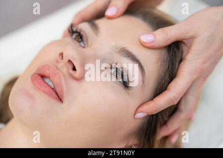 Healer performing set of 32 points of access bars on young woman head, stimulating positive change thoughts and emotions. Alternative medicine concept Stock Photo