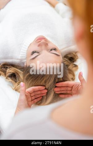 Healer performing set of 32 points of access bars on woman head, stimulating positive change thoughts and emotions. Alternative medicine concept Stock Photo