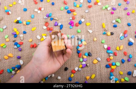 Little chair in hand amid colorful pebbles on canvas Stock Photo - Alamy