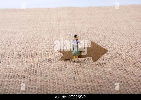 Figurine woman led by an arrow on canvas background Stock Photo