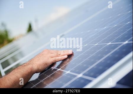 Engineers hand on new solar panel. Reneweble energy in modern life. Close up view of man hand on PV battery. Stock Photo