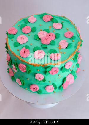 green icing frosted cake with sugar paste roses and pearls topping decoration all around the shape isolated on studio Stock Photo
