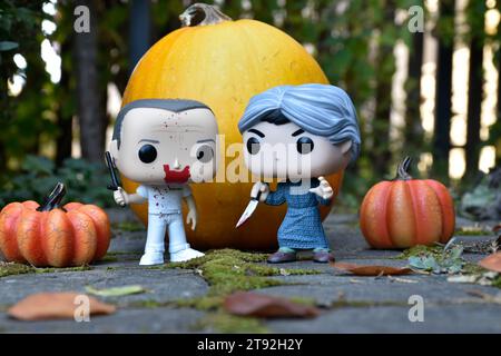 Funko Pop action figures of horror characters Hannibal Lecter and Norman Bates. Halloween, spooky season, pumpkins, decor, moss, autumn garden. Stock Photo