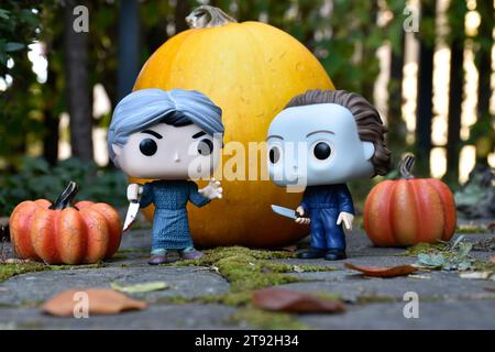 Funko Pop action figures of horror characters Norman Bates and Michael Myers. Halloween, spooky season, pumpkins, decor, moss, autumn leaves, garden. Stock Photo