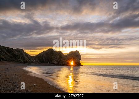 Durd|e Door, Dorset, UK.  22nd November 2023.  UK Weather:  A spectacular sunrise at Durdle Door in Dorset with the rising sun shining through the keyhole of the famous limestone rock sea arch.  Picture Credit: Graham Hunt/Alamy Live News Stock Photo