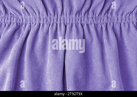 Purple corduroy fabric gathered with elastic close-up. Velveteen texture with folds and drapery. Cloth surface, textile background, wallpaper, backdro Stock Photo