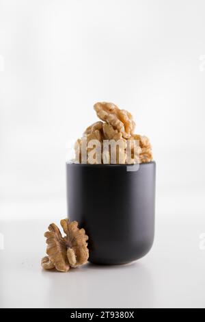 Walnuts in a black glass on a white wooden table Stock Photo