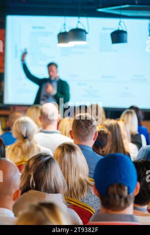 Back view of multiethnic business professionals listening to speaker giving presentation in conference hall Stock Photo