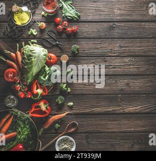Food background with organic vegetables, healthy ingredients and kitchen utensils on dark rustic wooden table. Top view. Copy space. Stock Photo