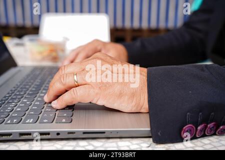 closeup of unrecognizable businessman with a suit typing on laptop keyboard outside Stock Photo