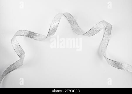 Photo of a silver glitter ribbon curling on a white background Stock Photo