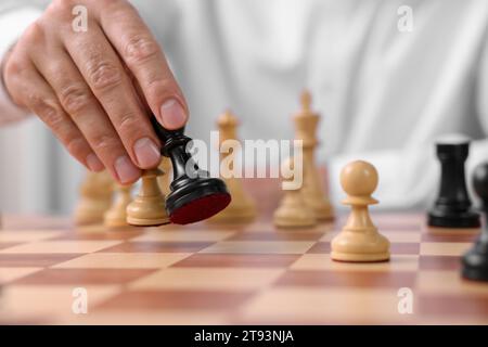 Man moving chess pieces at checkerboard, closeup Stock Photo