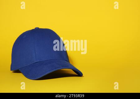Stylish blue baseball cap on yellow background, space for text Stock Photo