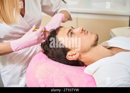 Cosmetologist gives injections to a clients scalp Stock Photo