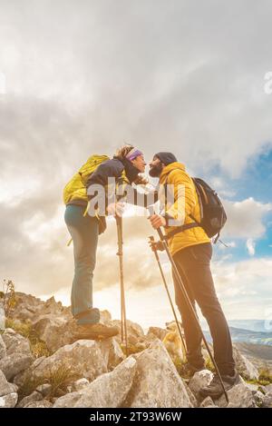 hiker couple kissing upon reaching the top of the mountain. two mountaineers hiking in the mountains with their dog. outdoor sports. Stock Photo