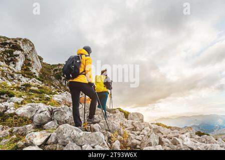 two mountaineers on a hiking trail equipped with a backpack, warm clothes and trekking poles. couple hiking in high mountains Stock Photo