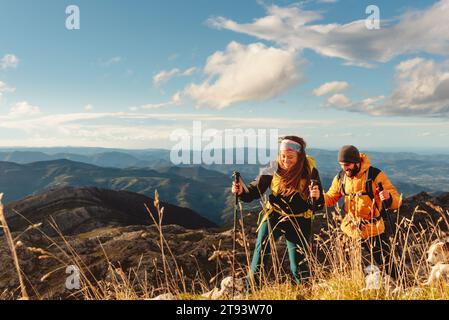 couple of hikers equipped with backpacks, trekking poles and warm clothes doing a mountain route. outdoor sports and adventure. Stock Photo