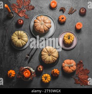 Autumn table setting with various pumpkins, plates, cutlery and fall leaves at grey background. Top view Stock Photo