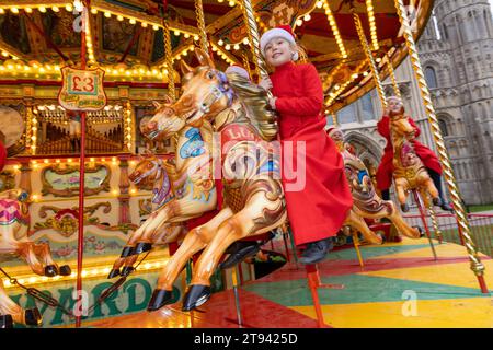 Choristers from Ely Cathedral  going for a spin on the  traditional carousel at the city’s Christmas market  after early morning choir practice . Stock Photo