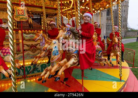 Choristers from Ely Cathedral  going for a spin on the  traditional carousel at the city’s Christmas market  after early morning choir practice . Stock Photo