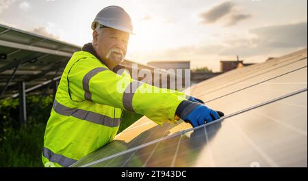 Senior engineer assembling solar panels at an energy farm during sunset. Alternative energy ecological concept image. Stock Photo