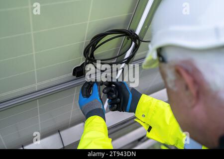 Close-up of an engineer connecting cables on solar panels. Alternative energy ecological concept image. Stock Photo