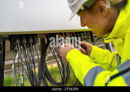 Technician using a voltage tester on a solar field's electrical distribution box. Alternative energy ecological concept image. Stock Photo