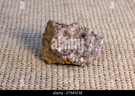 Pelitic Schist Rock isolated on beige knitted fabric Background close up Stock Photo