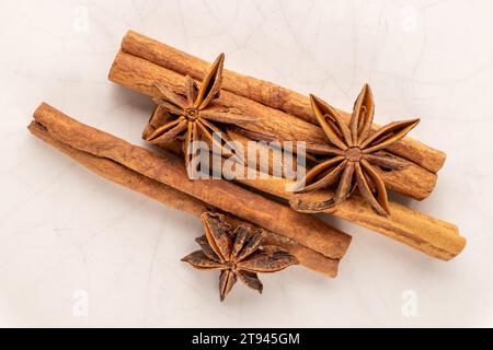 Three cinnamon sticks and three anise stars on a ceramic plate, macro, top view. Stock Photo