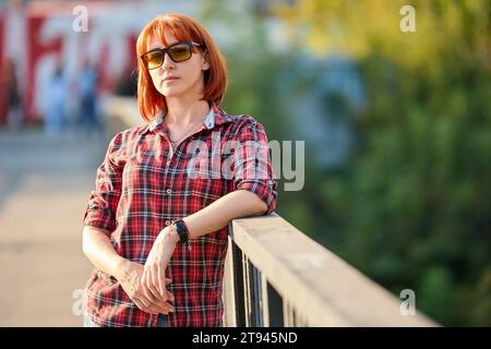 A redhead woman poses gracefully in the warm glow of an autumn sunset Stock Photo