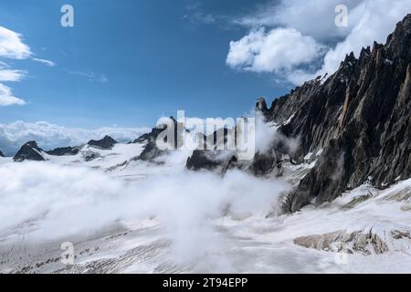 View of the rugged mountain ridges on the Italian French border leading up toward the Mont Blanc with low clouds moving across the glacier in Chamonix Stock Photo