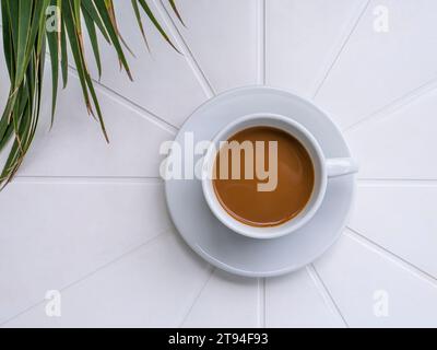 Top down view of a porcelain cup with coffee on a round, white table. Stock Photo